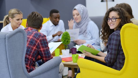 Gruppe junger Menschen mit Migrationshintergrund sitzen in einem Stuhlkreis. Sie sind Teilnehmende des Aktivierungscoachings IADE zur Verbesserung ihrer Sprachkompetenz und beruflichen Chancen.